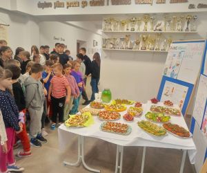 Uczniowie szkoły przed wystawą plakatów i stołem ze zdrowymi przekąskami