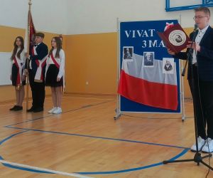 Uczeń klasy siódmej jako konferansjer oraz troje uczniów w poczcie sztandarowym w galowych strojach