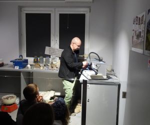 Przewodnik pokazuje uczniom sposób szlifowania kamieni ozdobnych w Muzeum