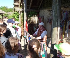 Uczniowie słuchają opowieści tkaczki w Osadzie Średniowiecznej w Hucie Szklanej