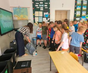 Dzieci segregują śmieci do odpowiednich pojemników