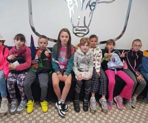 Uczniowie siedzą na tle godła miasta Hrubieszowa