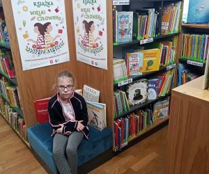 Uczennica siedzi przy regałach z książkami