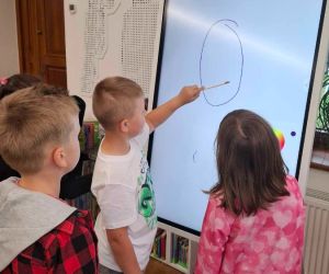 Uczniowie rysują na tablicy interaktywnej