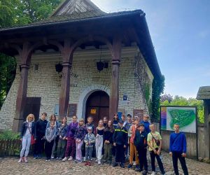 Uczniowie z opiekunem stoją przed muzeum