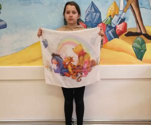 Dziewczynka trzyma uszytą poszewkę na poduszkę