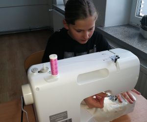 Uczennica szyje na maszynie