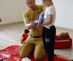 Strażak pokazuje jak wykonać opatrunek uciskowy