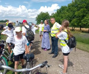 Grupa uczniów z przewodnikiem i właścicielką gospodarstwa lawendowego stoi przy polu lawendowym