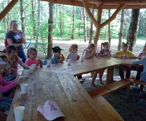 Uczniowie siedzą w drewnianej altanie