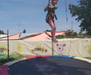 Dziewczynka podwieszona na linach skacze na trampolinie