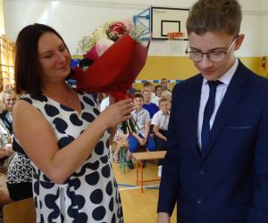 Uczeń klasy ósmej wręcza bukiet kwiatów wychowawczyni