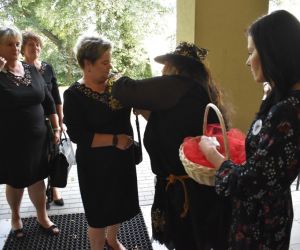 Na zdjęciu widocznych jest kilka osób, stojących przed budynkiem.
