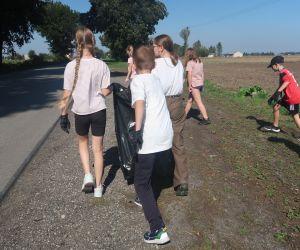 Uczniowie zbierają śmieci w okolicy szkoły.