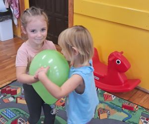 Dziewczynki tańczą z balonem.
