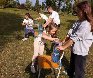 Dzieci podczas wyścigu przelewają wodę ze szklanek do plastikowych butelek