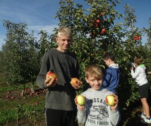 Dwóch uczniów trzyma w dłoniach zebrane jabłka