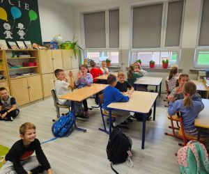 Dzieci w ławkach wykonują rozgrzewkę (klaskanie w dłonie w rytym muzyki)