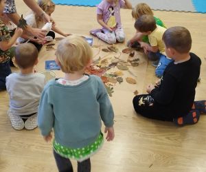 Przedszkolaki wyklejają koronę drzewa liśćmi