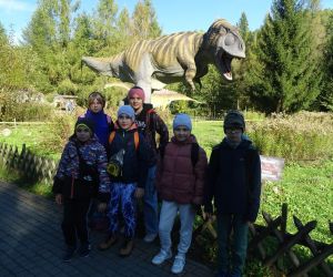Uczniowie klasy czwartej i piątej na tle modelu dinozaura