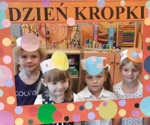 Cztery dziewczynki w strojach w kropki pozują w kropkowanej ramie okolicznościowej