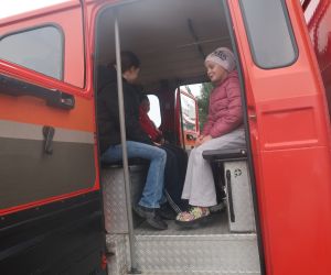 Dzieci siedzą w wozie strażackim