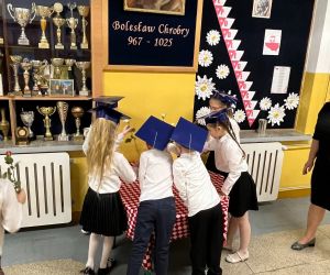 Uczniowie składają kwiaty pod wizerunkiem patrona szkoły