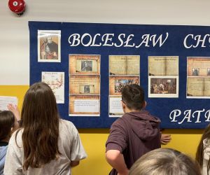 Uczniowie zapoznają się z informacjami o patronie zamieszczonymi na gazetce szkolnej