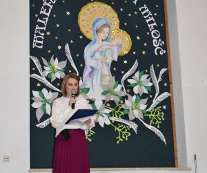 Kobieta przemawia na scenie wewnątrz budynku.