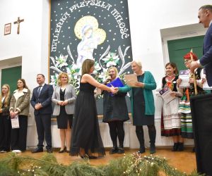 Grupa osób na scenie wewnątrz budynku. Odbiór statuetek, laureaci Konkursu.